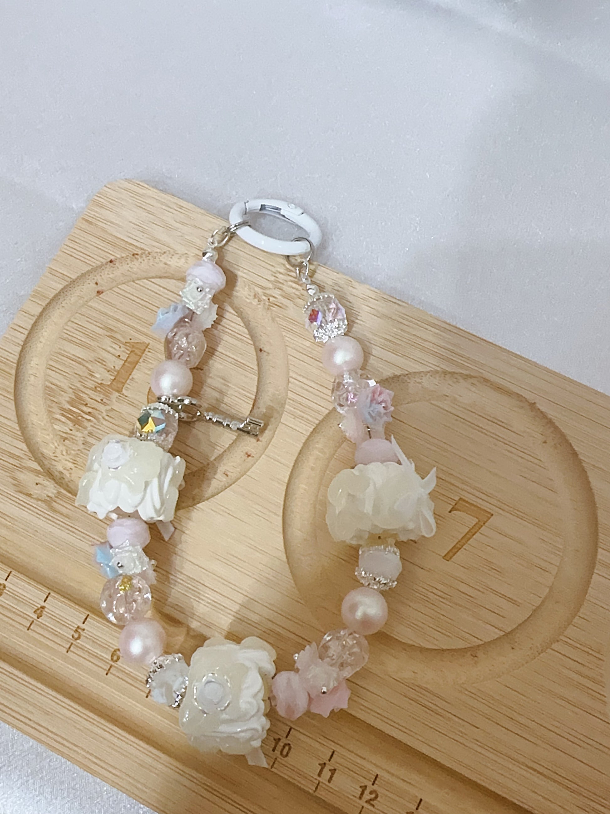 Decorative keychain with floral and bead design on a wooden surface