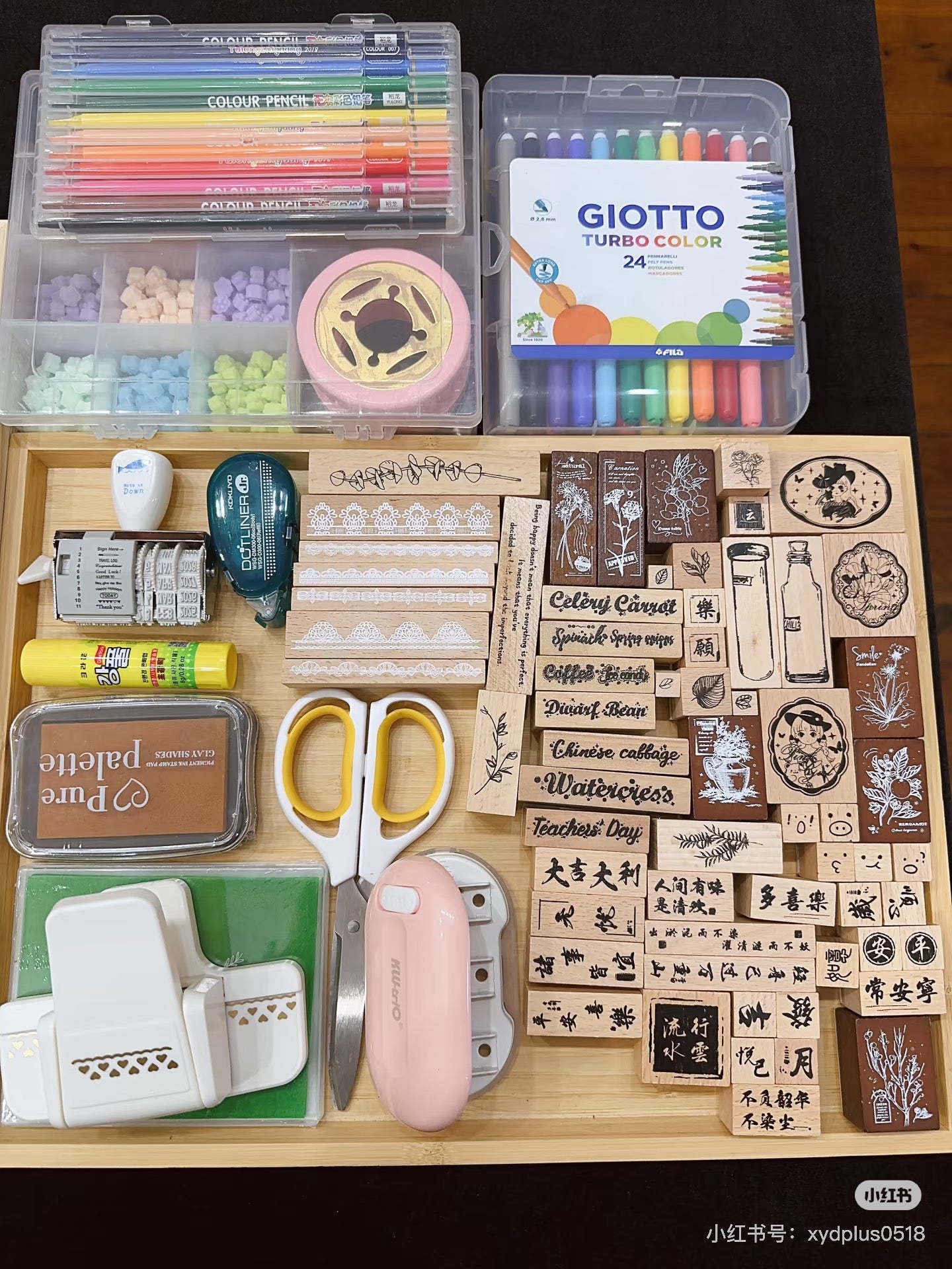Stationery items including colored pencils, markers, stamps, and scissors on a wooden surface.