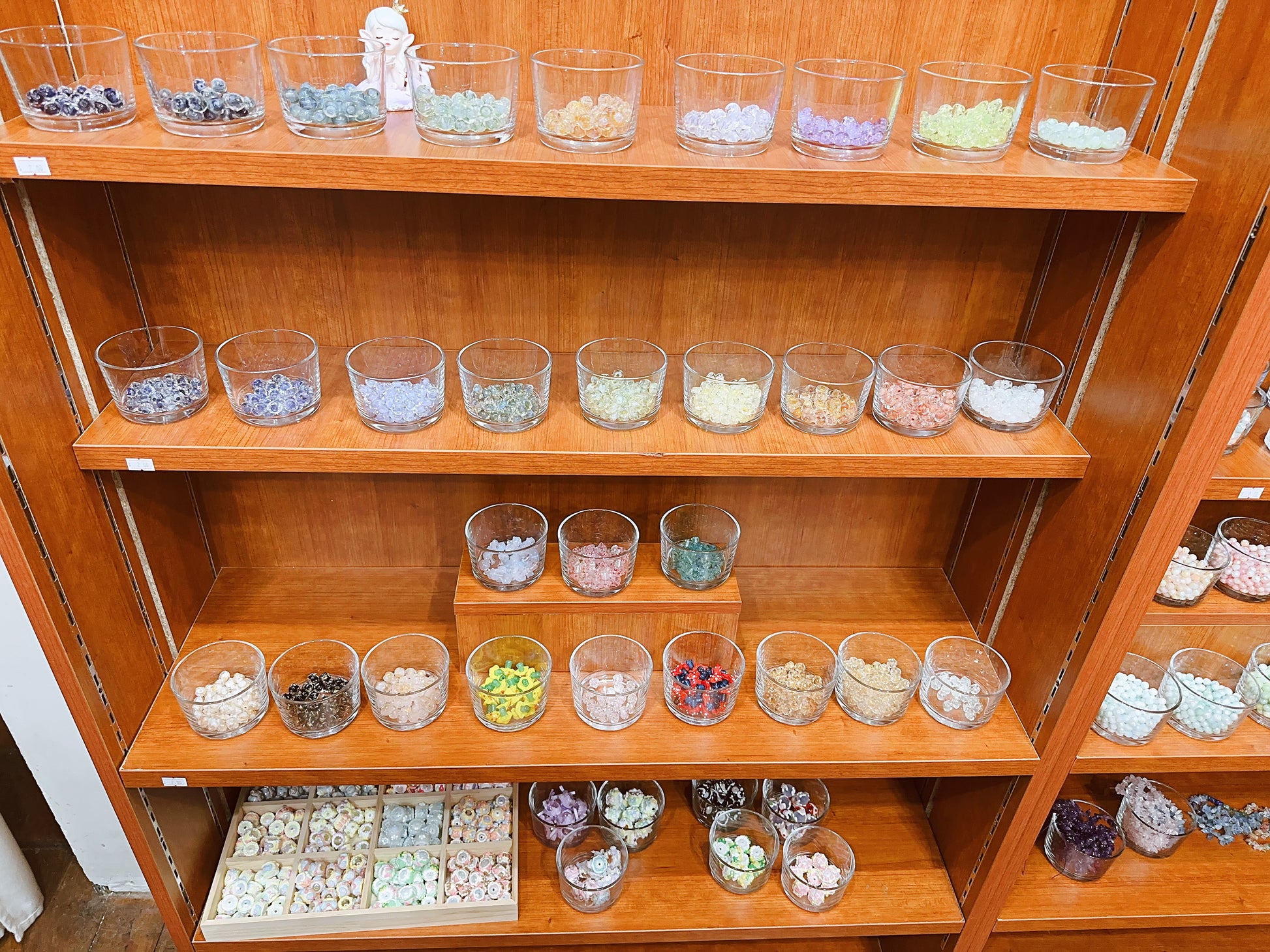 Wooden shelf with various small glass containers filled with different types of stones or crystals.