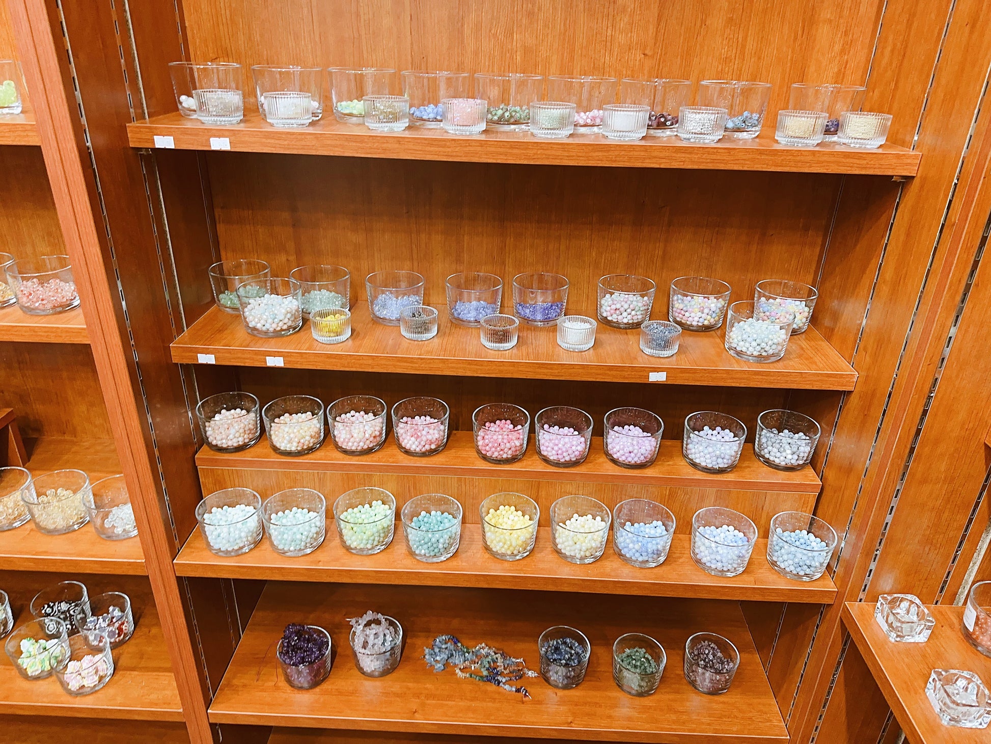 Wooden shelf with various small glass containers filled with colorful beads
