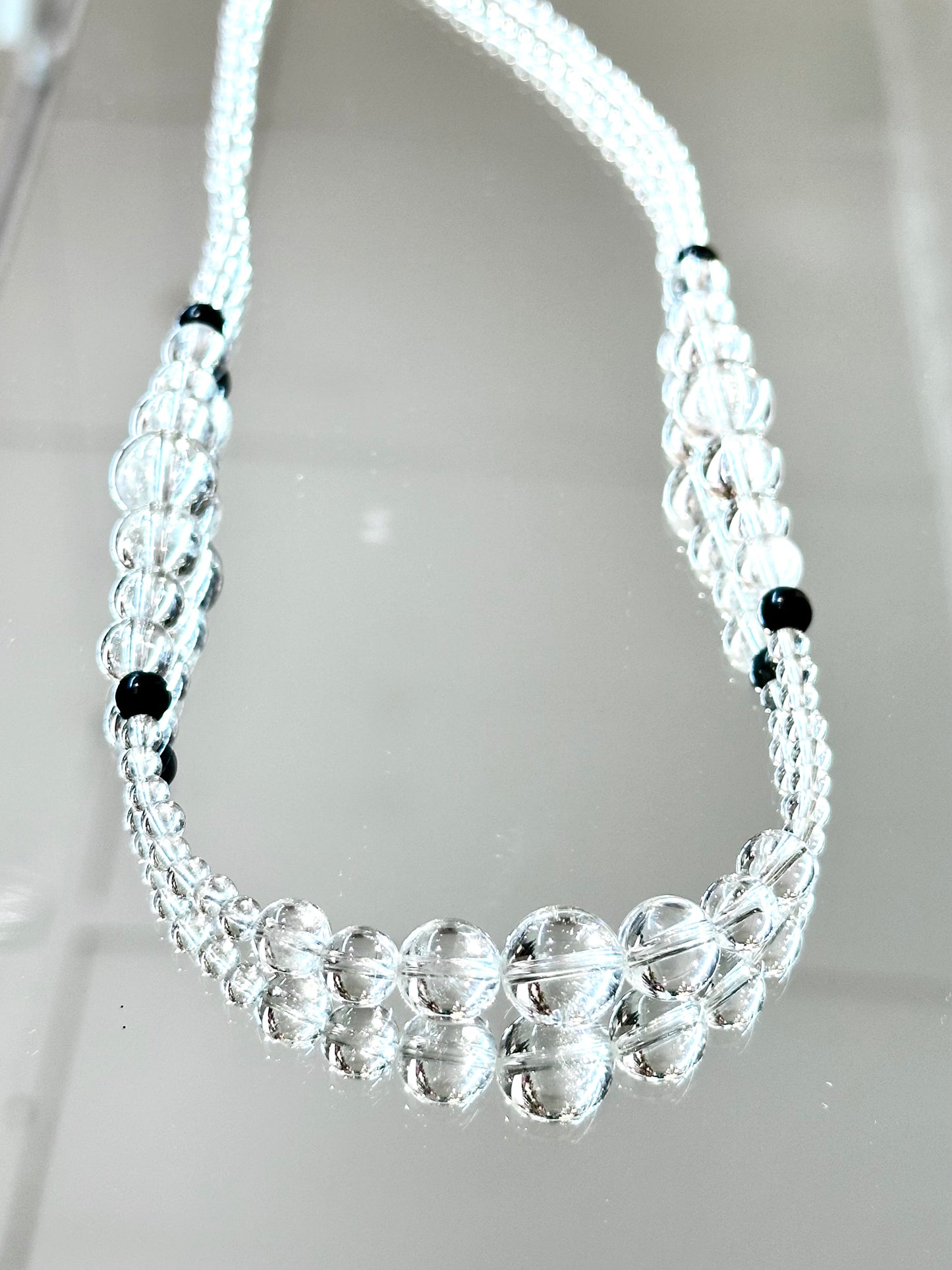 Beaded necklace with clear and black beads on a light gray background