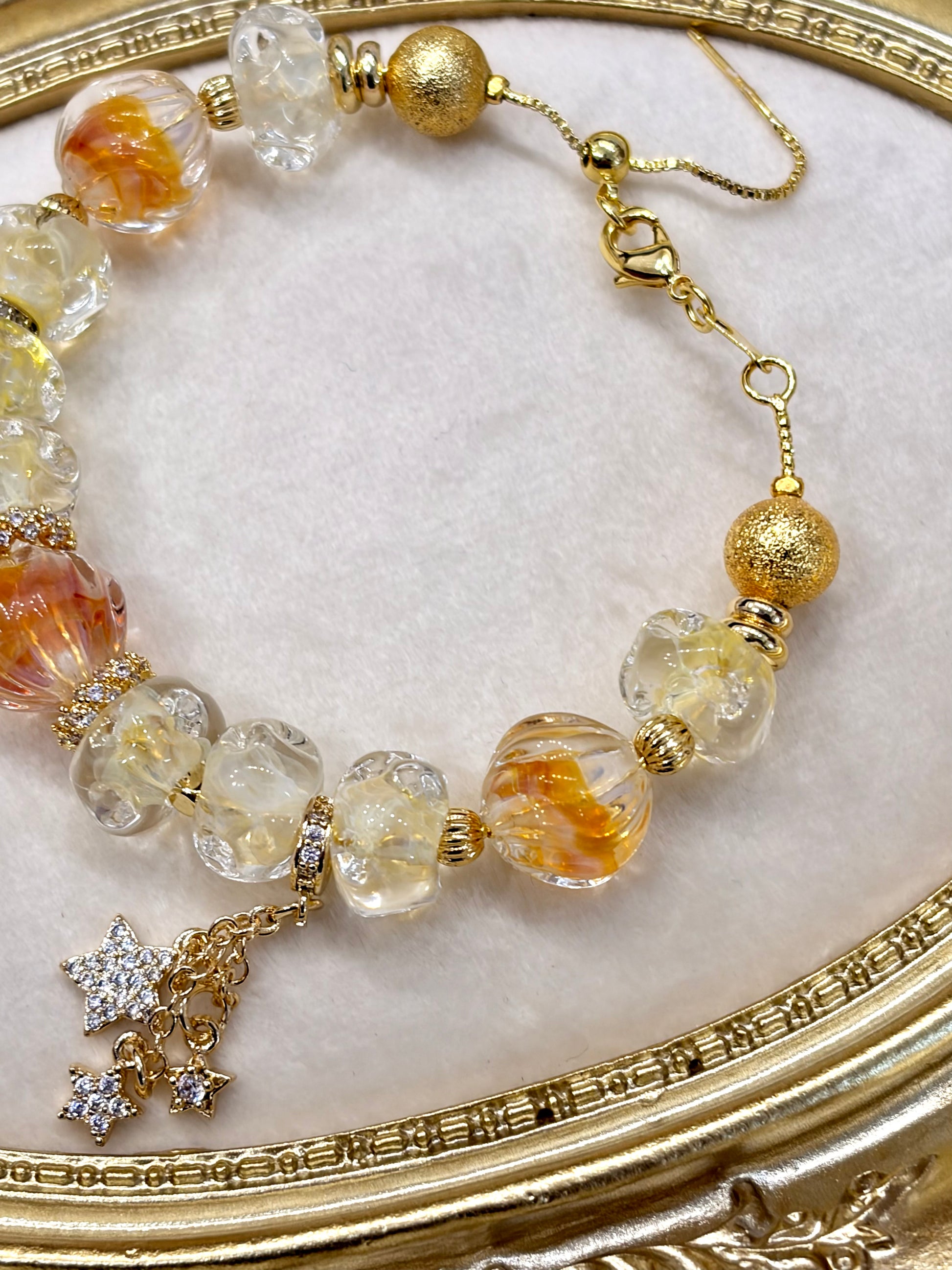 Bracelet with gold and clear beads on a decorative gold surface