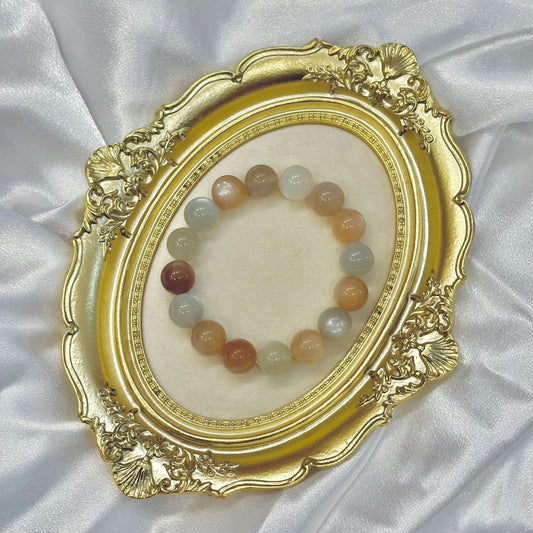 Handmade multicolor moonstone bracelet in peach, grey and white displayed in gold ornate frame — 13mm natural healing crystal jewellery by XYD PLUS